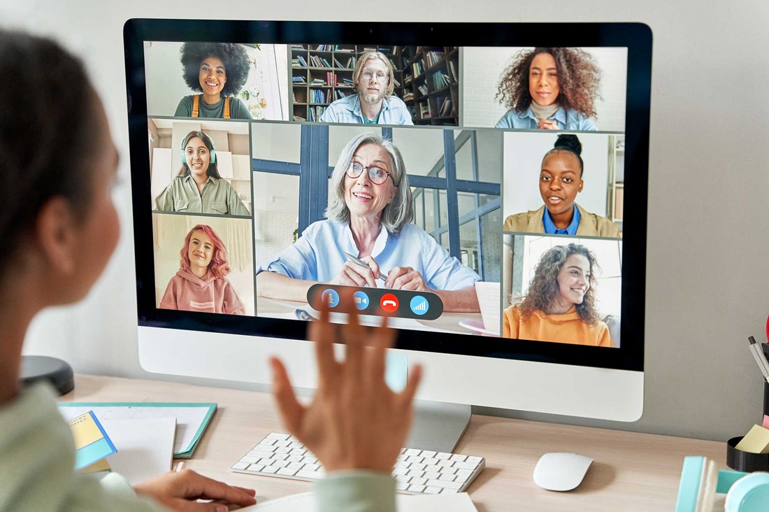 Junge Frau nimmt an einer Video-Konferenz statt - auf ihrem Bildschirm sind mehrere Teilnehmende zu sehen.