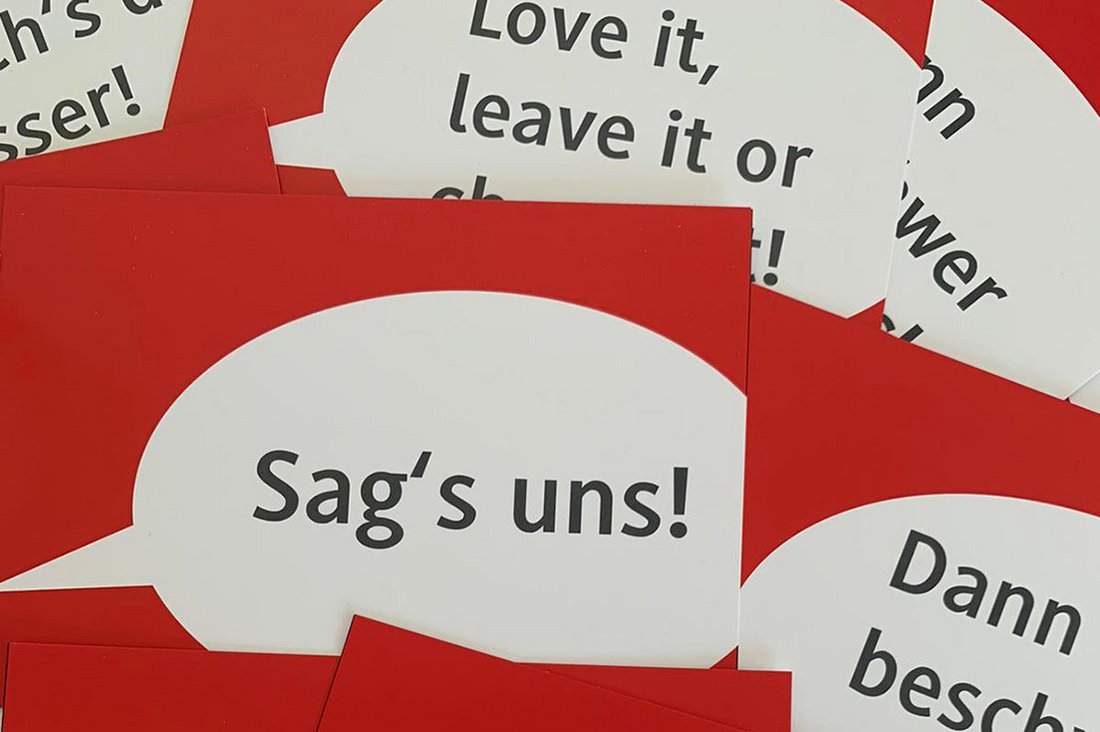 Plakat- und Postkartenmotiv: Kurze Handlungsaufforderungen wie z. B. "Sag's uns!" auf rotem Hintergrund