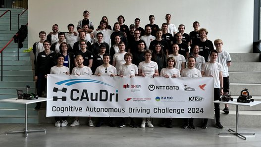 Die Teilnehmenden der CAuDri-Challenge 2024 Die Teilnehmenden der CAuDri-Challenge 2024 - Gruppenfoto im Neubau Technik. Die Teilnehmenden halten ein Banner mit der Aufschrift Caudri-Cup vor sich.