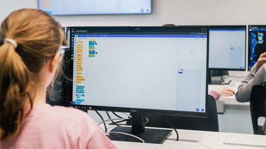 Detail-Ansicht eines Computer-Bildschirms, vor dem eine Teilnehmerin sitzt.
