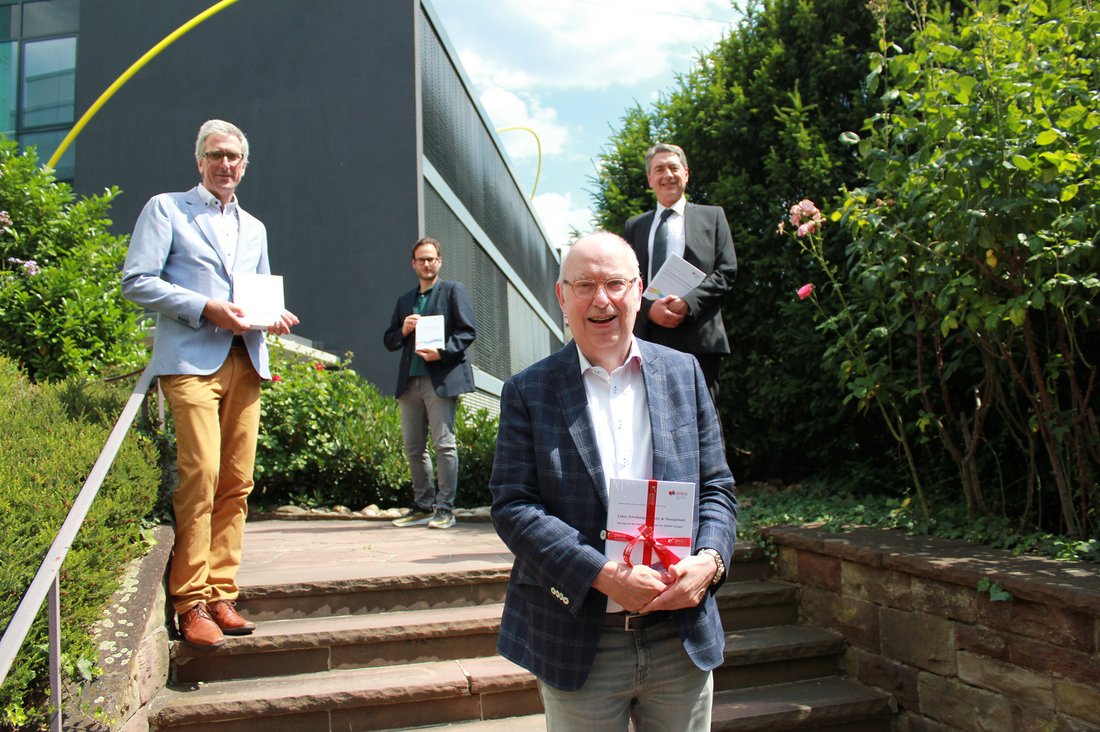 BU: Der geehrte Prof. Dr. Bernd Müllerschön mit Festschrift und den Herausgebern Prof. Stefan Fünfgeld, Benjamin Schiller und Prof. Dr. Joachim Weber