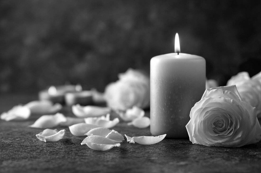 Weiße Rose und brennende Kerzen