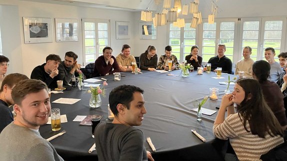 Gruppenbild - Teilnehmende an der Exkursion sitzen an einem runden Tisch. 