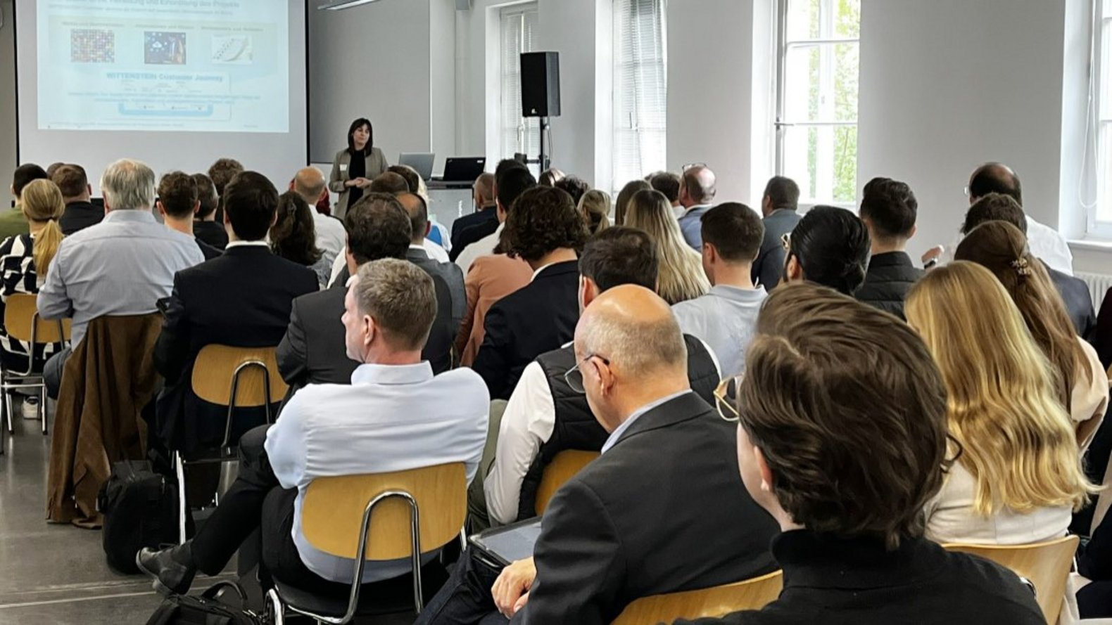 Publikum beim Technologietag, das dem Programmbeitrag von WITTENSTEIN SE. zuhört.