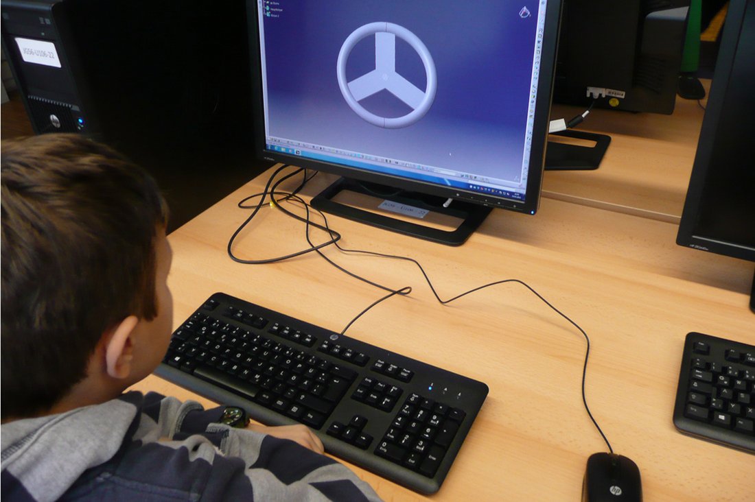 Ein Junge konstruiert am PC ein Gokart-Lenkrad.