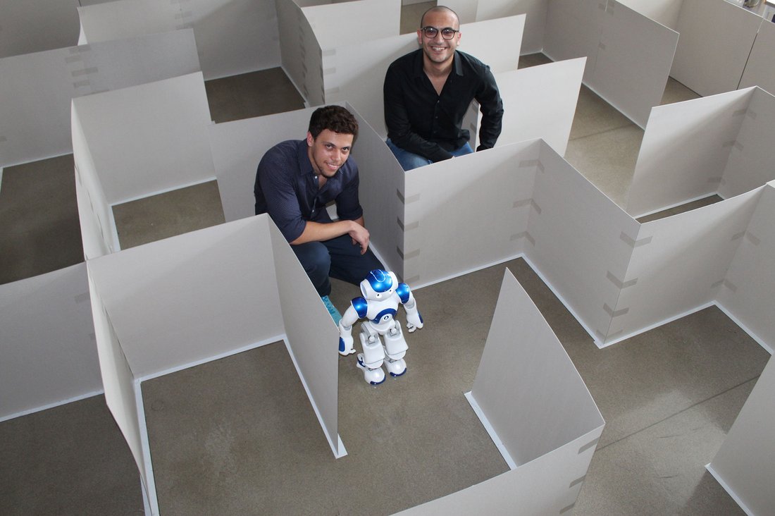 Die Gaststudenten Ahmed Mousa und Marwan Adel mit dem Roboter Nao im Labyrinth.