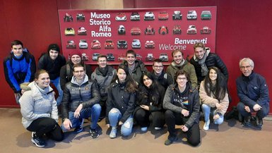 Die Studierendengruppe um Prof. Dr. Christian Götz Gruppenbild vor einem Plakat des Museo Storico Alfa Romeo