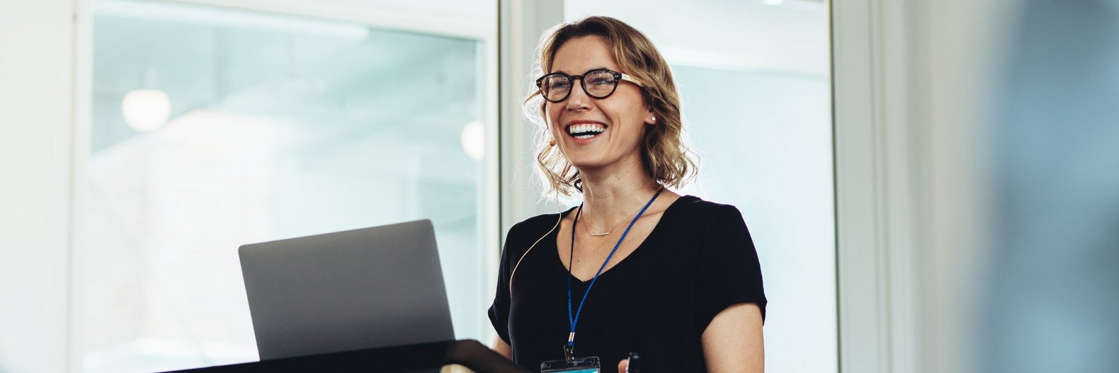 Dozentin während eines Vortrags - vor ihr auf dem Rednerpult steht ein Laptop.