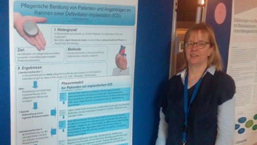 Anke Kampmann vor ihrem Poster „Pflegerische Beratung von Patienten und ihren Angehörigen im Rahmen einer Defibrillator-Implantation“ 