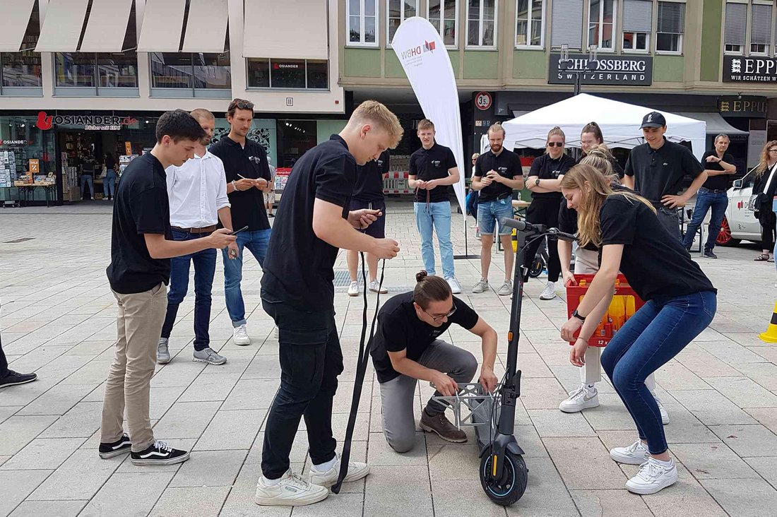 Drei Studierende installieren auf dem Stuttgarter Marktplatz die Transportmöglichkeit für eine Getränkekiste.