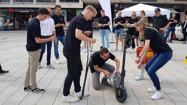 Drei Studierende installieren auf dem Stuttgarter Marktplatz die Transportmöglichkeit für eine Getränkekiste.