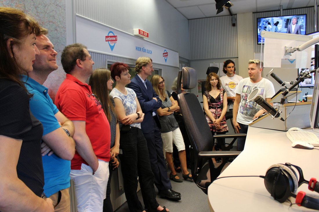 Radiomoderator Jens Meßmann (rechts) und Programmchef Alexander Heine (6. von links) zeigen den Teilnehmerinnen und Teilnehmern das Studio