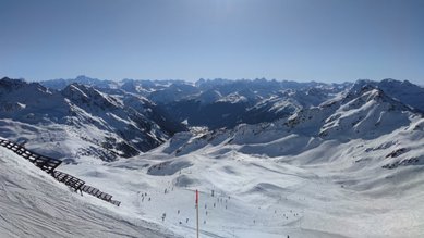 Skipiste und Bergpanorama bei strahlendem Sonnenschein