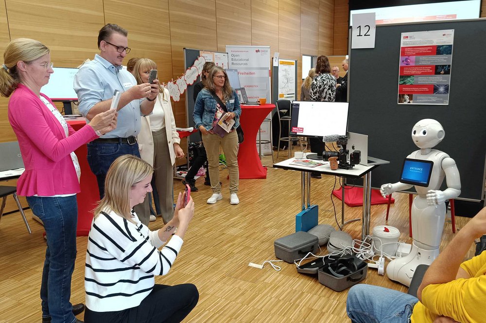 Roboter Pepper am Messestand des ZDT, der von mehreren Besucher*innen mit dem Smartphone fotografiert wird.