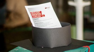 Nahaufnahme eines der Bachelor-Hüte mit einem Programmzettel.