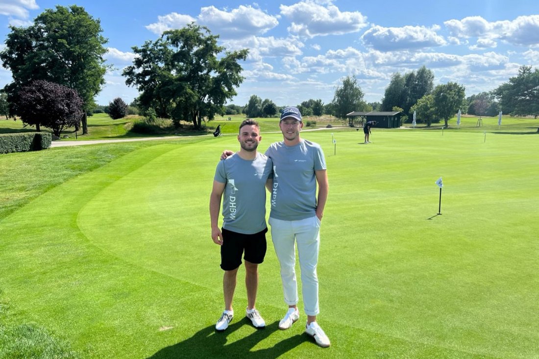 Die Studierenden Maxim Ament und Henri Ohlsen stehen auf dem Golfplatz.