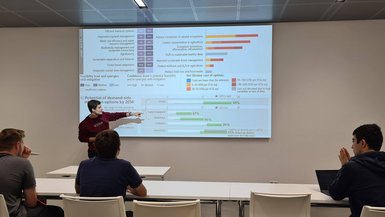 Vortrag zu Klimawandel, Ernährung und Landwirtschaft Der Vortragende steht vor einer Leinwand und erklärt darauf projizierte Daten und Informationen.