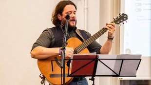 Portraitaufnahme David Lehmann mit Gitarre während der Abschlussfeier der Fakultät Sozialwesen 2025.