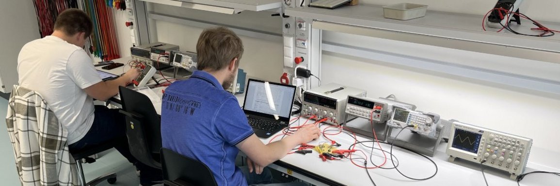 Labor Grundlagen der Elektrotechnik - Studierende bei der Versuchsdurchführung Im Labor Grundlagen der Elektrotechnik führen 2 Studierende Versuche durch. Blick über die Schulter auf die Versuchsanordnung.