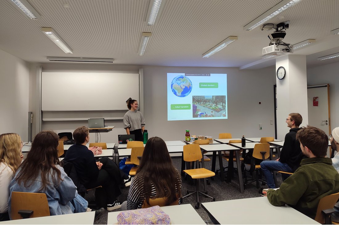 Alicia Böhm von Foodsharing im Vortragsraum, die Zuhörenden sitzen an Tischen verteilt im Raum.