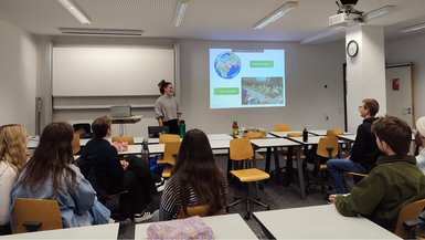 Alicia Böhm von Foodsharing informiert an der DHBW Stuttgart über die Vermeidung von Lebensmittelverschwendung. Alicia Böhm von Foodsharing im Vortragsraum, die Zuhörenden sitzen an Tischen verteilt im Raum.