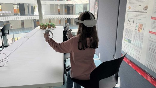 Mädchen mit VR-Brille, an einem Schreibtisch sitzend.