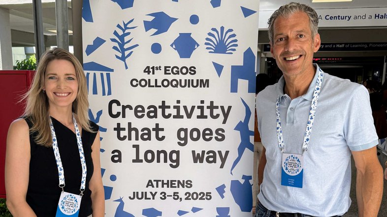 Prof. Dr. Elena Krause-Söhner und Prof. Dr. Christian Schaller stehen bei einem Roll-Up der Konferenz in Athen.  