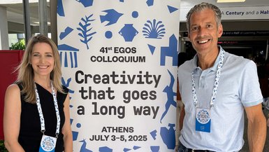 Prof. Dr. Elena Krause-Söhner und Prof. Dr. Christian Schaller stehen bei einem Roll-Up der Konferenz in Athen.  